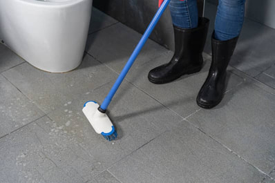 man in boots doing tile floor cleaning